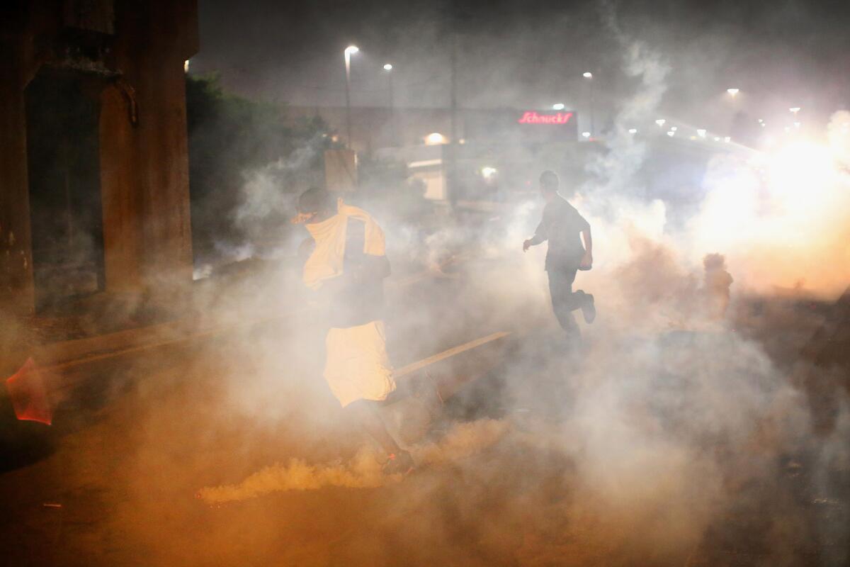 Tear gas fills the street in Ferguson, Mo., on Sunday evening. Blacks and whites differ sharply over whether the police response has "gone too far," a new poll shows.