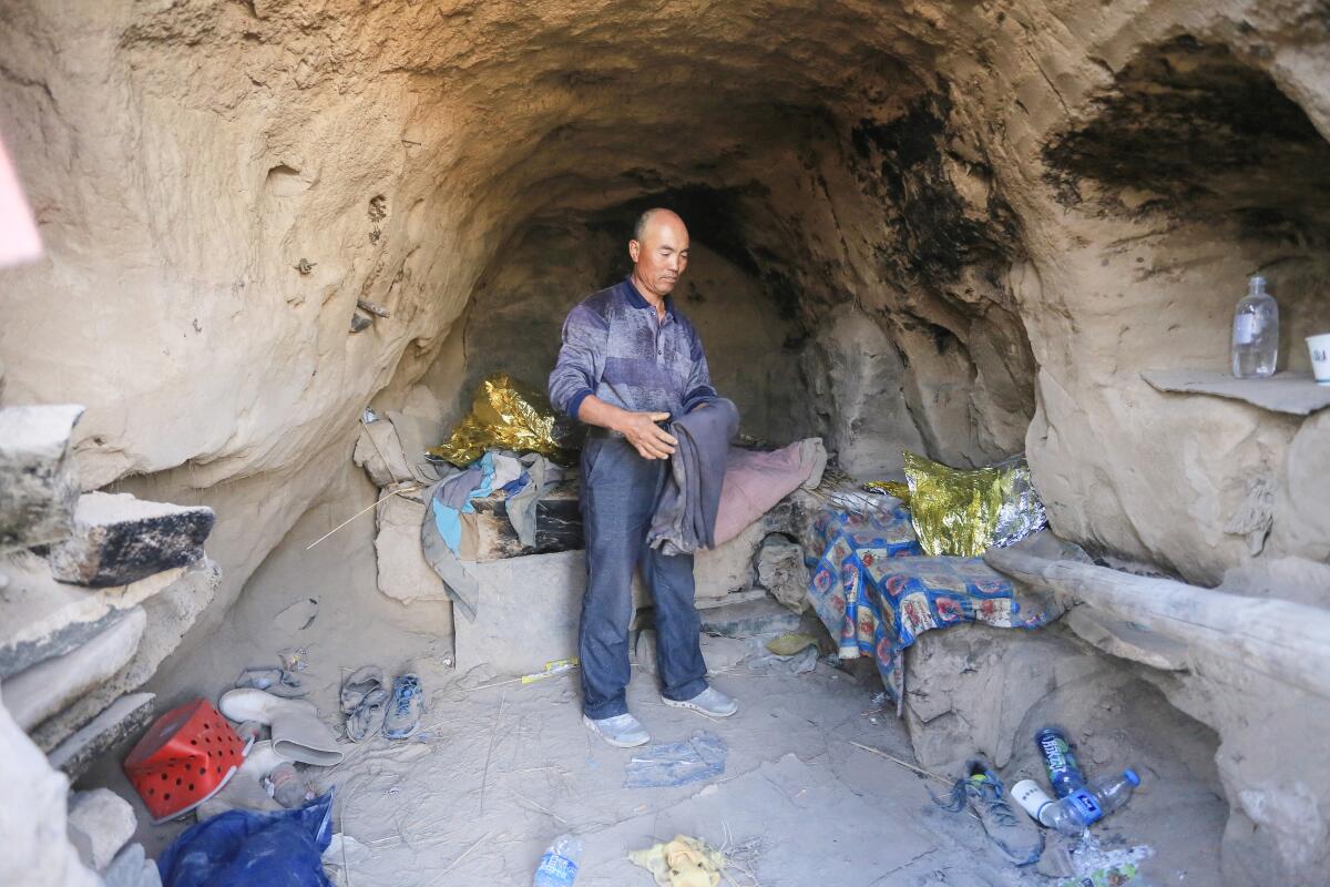 A man stands in a cave amid discarded Mylar blankets and water bottles. 