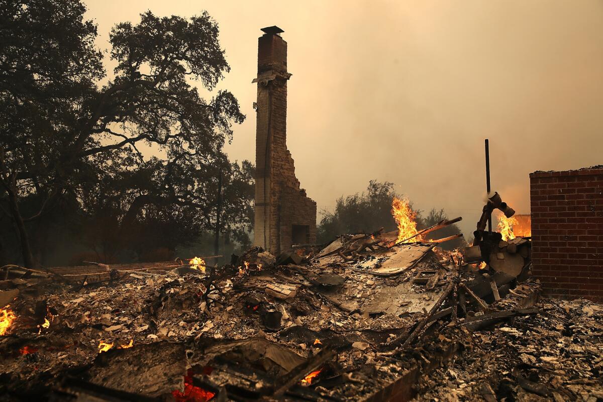 A firefighter hoses down a fire-ravaged home in Napa, Calif.