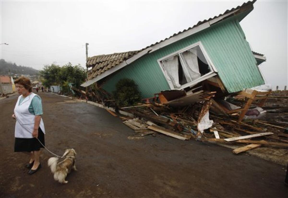 A woman stands in front of a damaged house after an earthquake in Pelluhue, some 322 kms, about 200 miles, southwest of Santiago, Sunday, Feb. 28, 2010. A 8.8-magnitude earthquake hit Chile early Saturday. (AP Photo/Roberto Candia)
