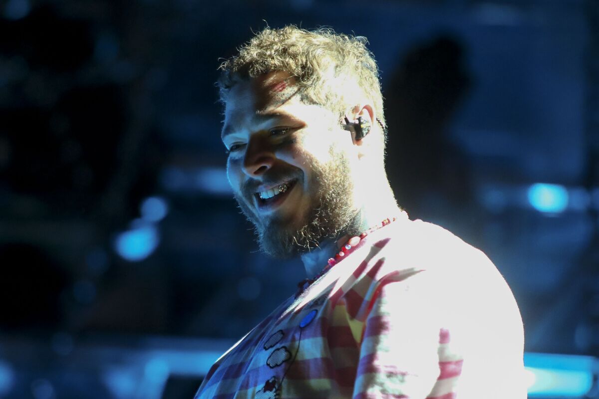 A bearded man wearing an earpiece and a striped shirt smiles