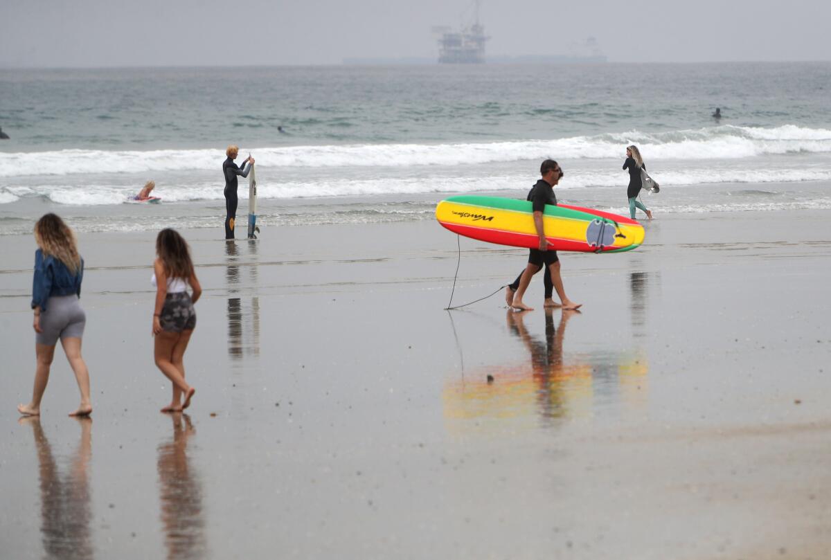 A couple of surfers leave the water at Huntington City Beach in April.