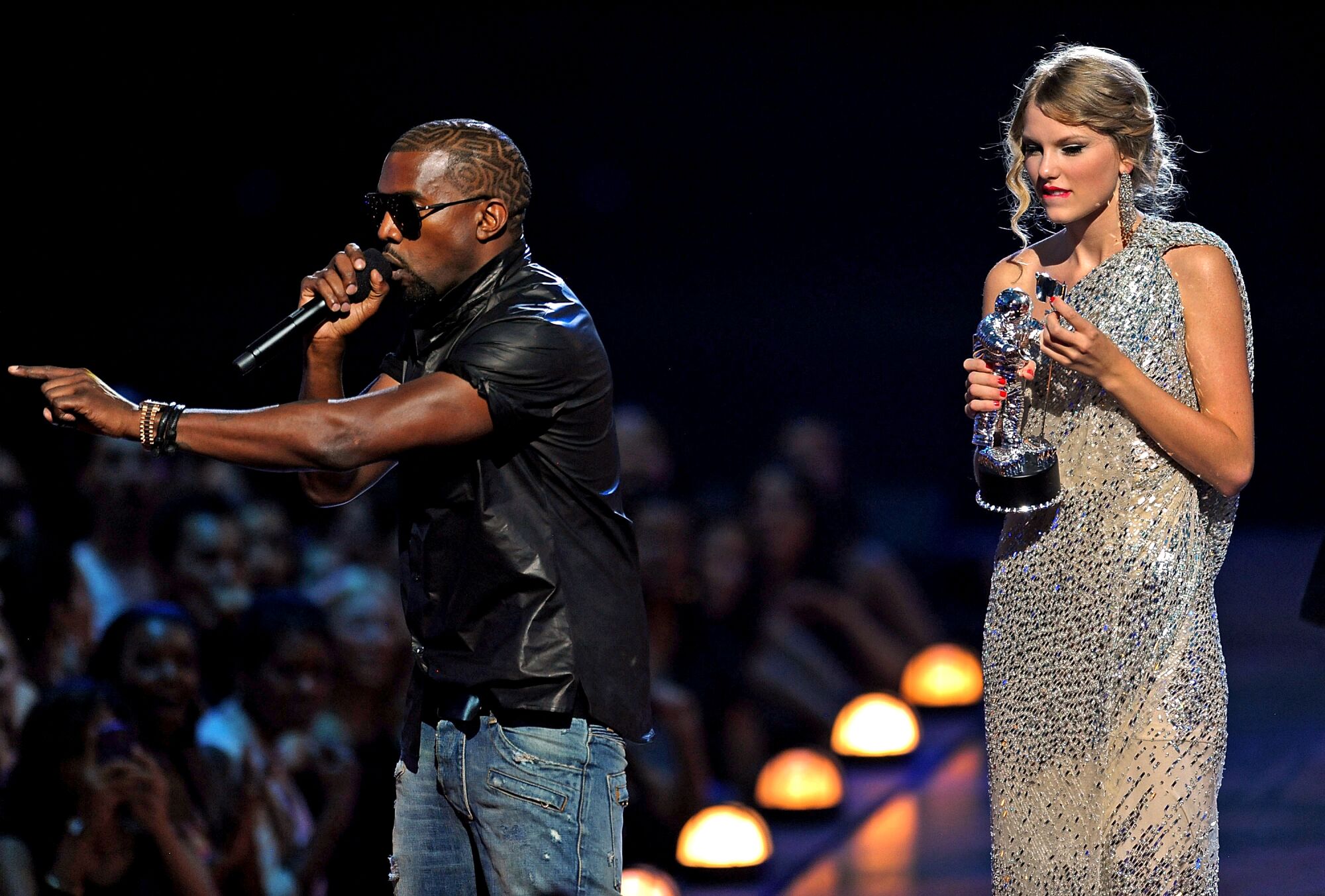 A male rap star interrupts a female pop star onstage at an awards show.