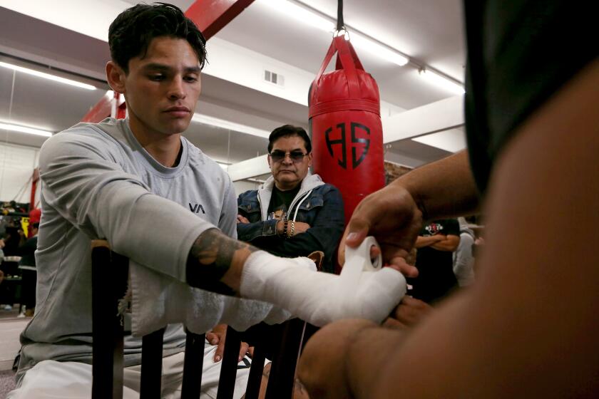 Van Nuys, CA - April 04: Lightweight boxer Ryan Garcia gets his hands wrapped for a sparring session at Ten Goose Boxing Gym in Van Nuys as his father Henry, right, looks on. Garcia is prepping for his big fight against Gervonta Davis later this month in Las Vegas. (Luis Sinco / Los Angeles Times)