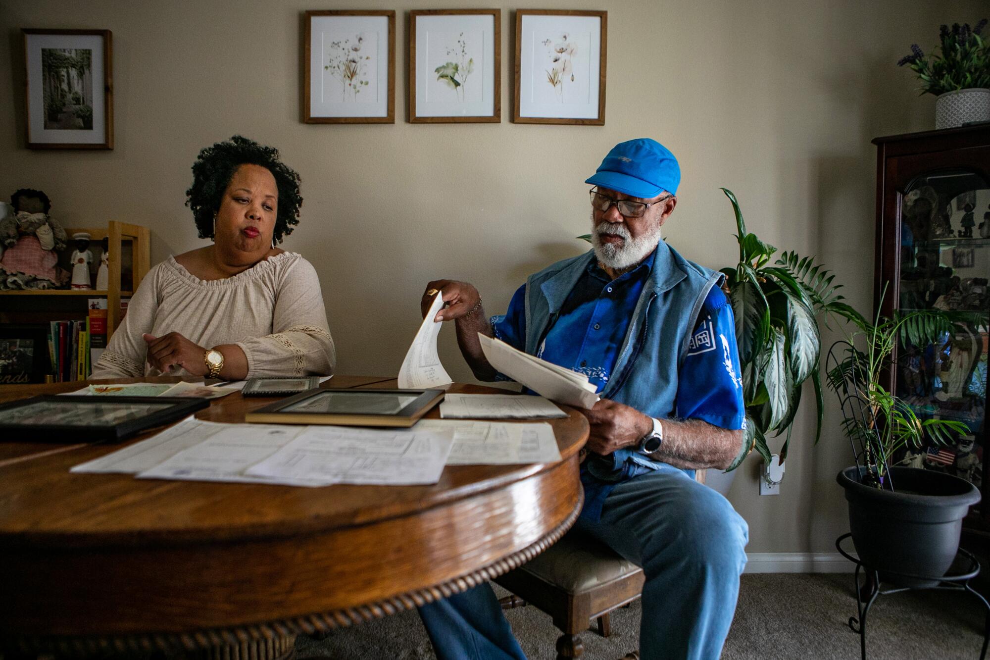 A woman and a man look at a table full of old family documents and pictures.