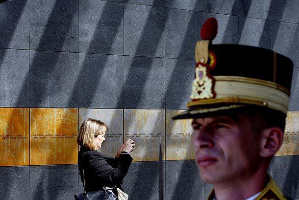 A woman takes a picture of victims' engraved names as a Romanian presidential honor guard soldier stands at attention inside the newly inaugurated Holocaust memorial in central Bucharest on Thursday. Romania erected the Holocaust memorial to commemorate the killing of more than a quarter-million Jews and Roma by the Nazi-allied Romanian authorities during World War II.