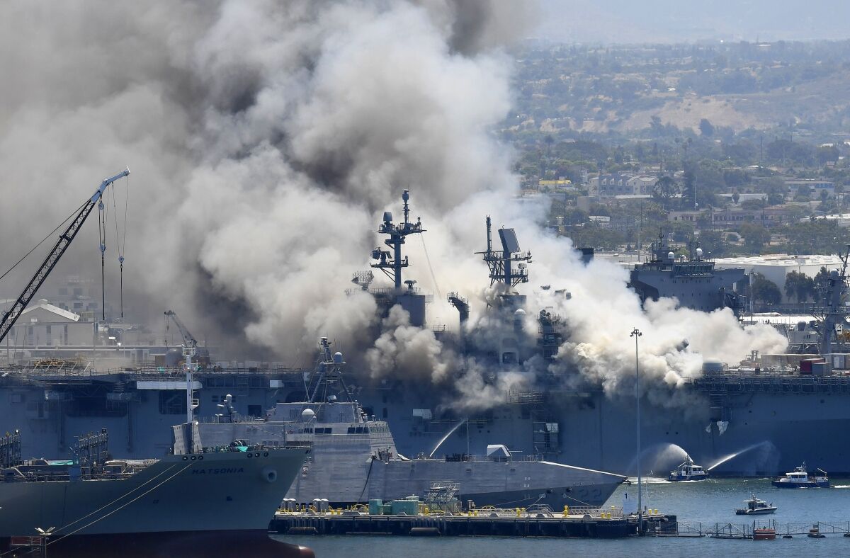 FILE - In this July 12, 2020, file photo, smoke rises from the USS Bonhomme Richard after an explosion and fire on board the ship at Naval Base San Diego. The Navy will hold a hearing Monday, Dec. 13, 2021, to review whether there is enough evidence to order a court martial for a San Diego-based sailor charged with setting the fire that destroyed the USS Bonhomme Richard in the summer of 2020. (AP Photo/Denis Poroy, File)
