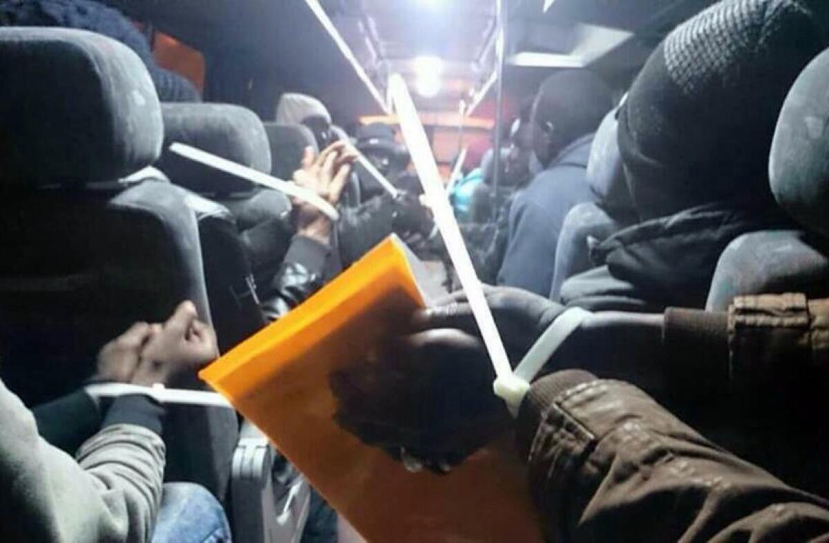 Sudanese are shackled with plastic zip-ties on a bus headed to a detention facility near the Amman airport in Jordan in December.