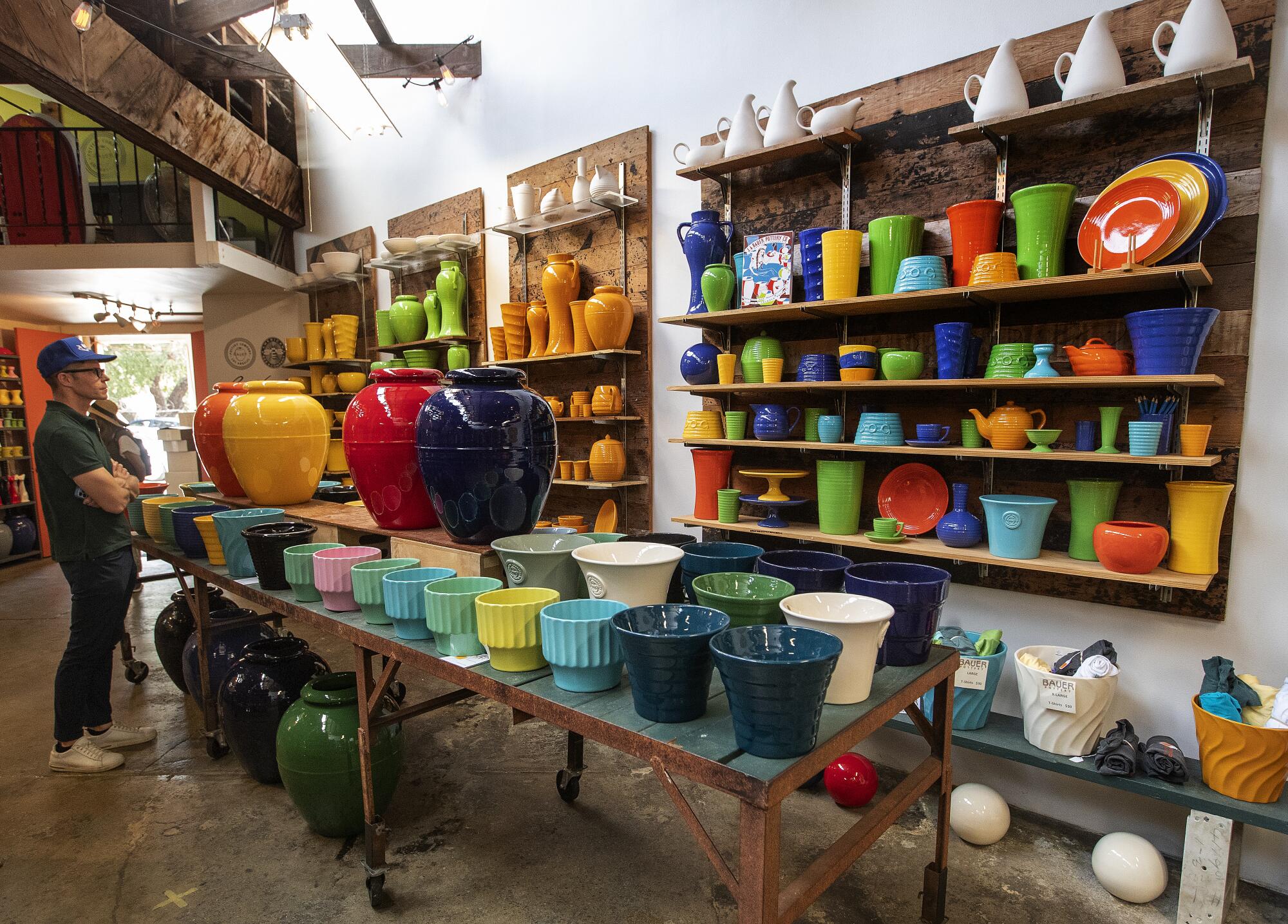 a man shops along shelves of colorful Bauer pottery 
