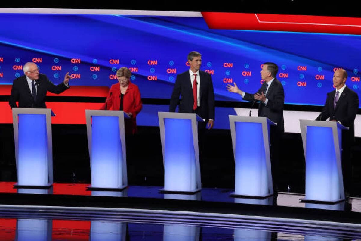 Sen. Bernie Sanders, left, and former Colorado governor John Hickenlooper, second from right, speak while Sen. Elizabeth Warren, former Texas congressman Beto O'Rourke and former Maryland congressman John Delaney look on during the first night of the Democratic presidential debates in Detroit on Tuesday. Twenty Democratic presidential candidates were split into two groups of 10 to take part in the debate sponsored by CNN held over two nights at Detroit’s Fox Theatre.