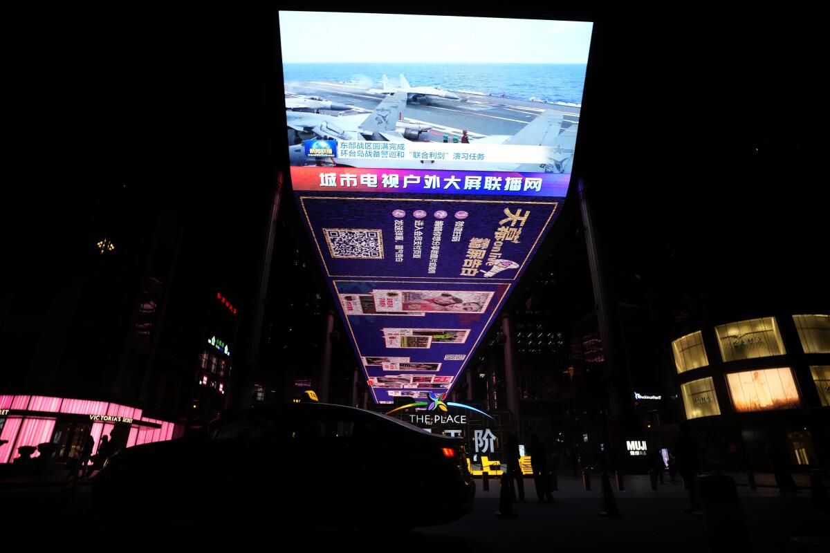 An outdoor TV screen in Beijing shows Chinese fighter jets on an aircraft carrier.