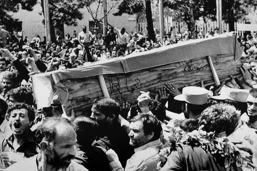 FILE - In this July 7, 1988 file photo, Iranian mourners carry one of 72 caskets to the Cemetery of Martyrs after attending a "Death to America" rally outside the Majlis, or Iranian parliament, in Tehran, Iran. The Western allegation that Iran shot down a Ukrainian jetliner and killed 176 people offers a grim echo for the Islamic Republic, which found itself the victim of an accidental shootdown by American forces over 30 years ago. (AP Photo/Greg English, File)