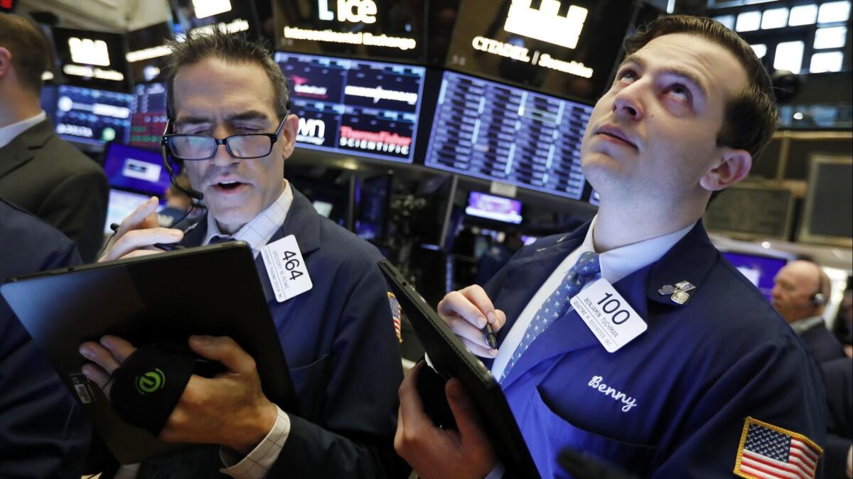 Traders Gregory Rowe, left, and Benjamin Tuchman work on the floor of the New York Stock Exchange.