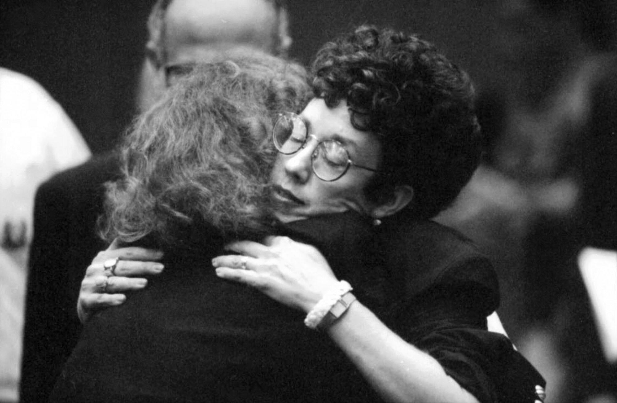 Two women embrace.