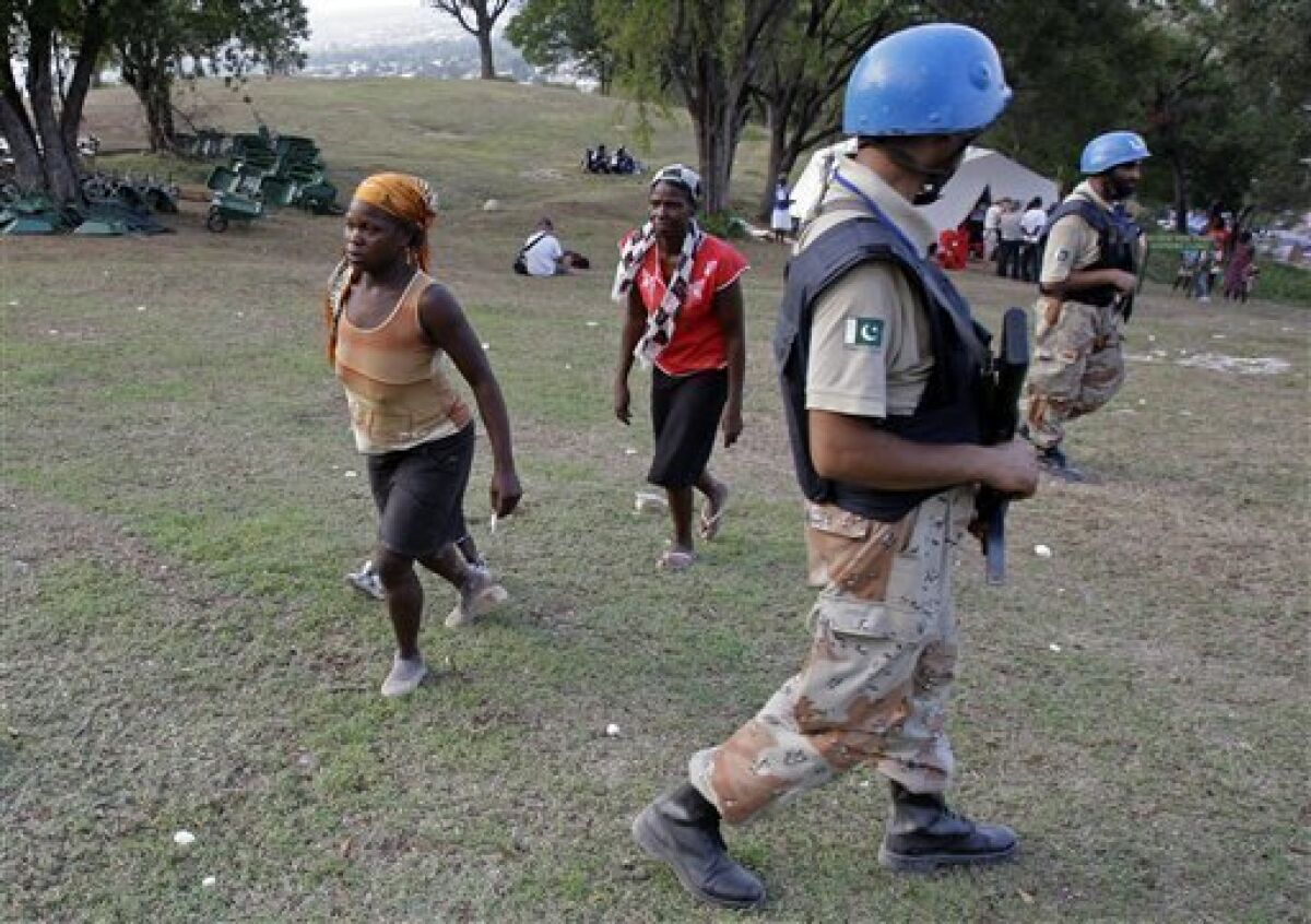 In this photo taken March 14, 2010, two women walk toward the field hospital run by the Jenkins-Penn Haiti Relief Operation, as UN peacekeepers from Pakistan arrive to provide security for the visit of U.N. Secretary-General Ban Ki-moon, at the makeshift camp for earthquake survivors in the Petionville Golf Club in Port-au-Prince. Women, girls and children as young as 2 years old, already traumatized by the loss of homes and loved ones in Haiti's earthquake, now are falling victim to rapists in sprawling and unmanageable tent cities that have become home to hundreds of thousands of people. (AP Photo/Andres Leighton)