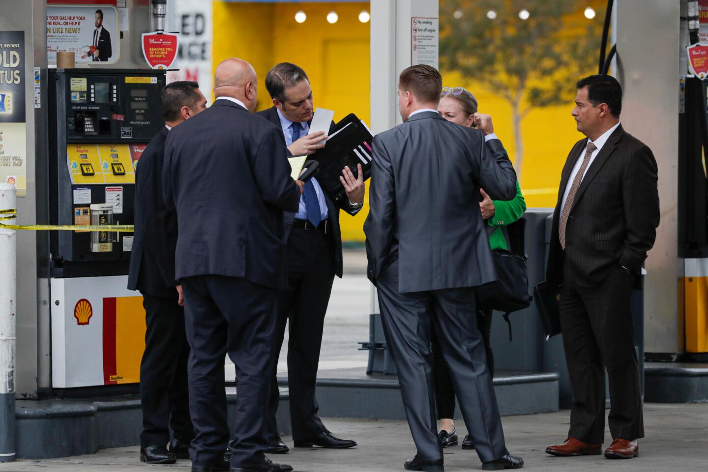 L.A. detectives confer at a gas station where two people were wounded, one fatally, in a shooting in North Hollywood.