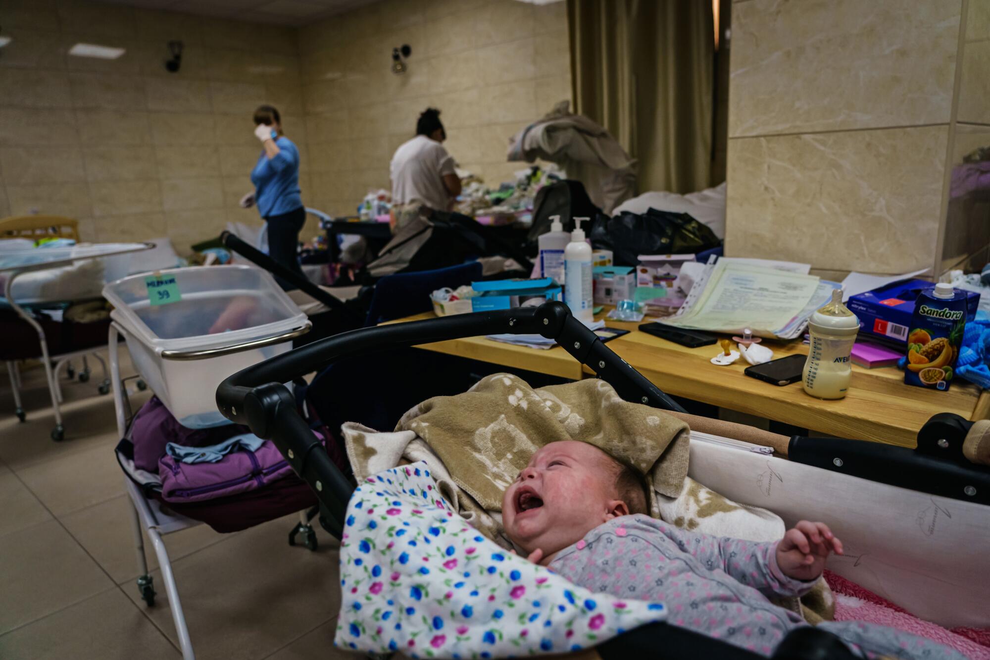 A baby cries for attention in a stroller in a makeshift nursery underground in the outskirts of Kyiv, Ukraine.