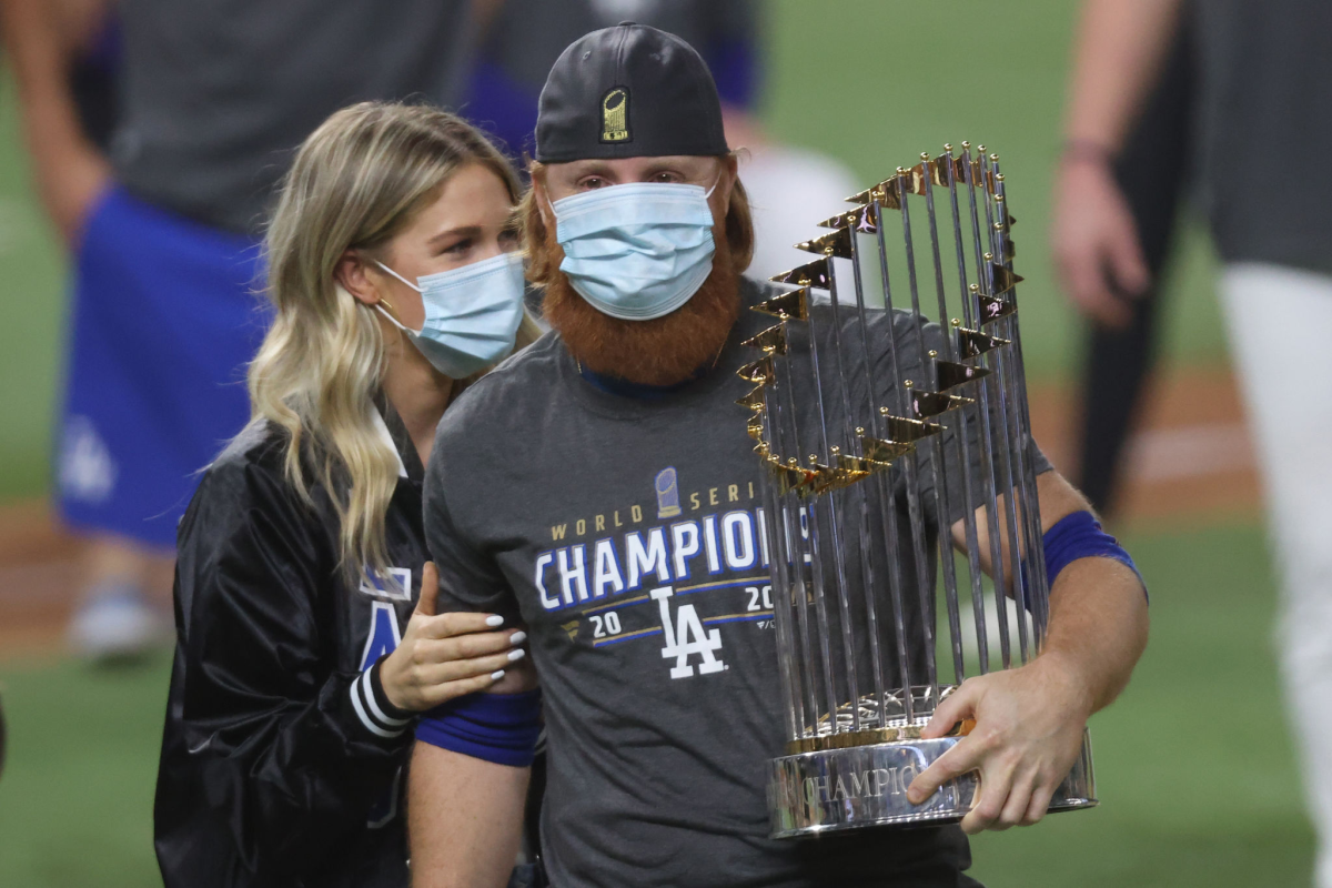 Dodgers third baseman Justin Turner holds the World Series championship trophy while standing next to his wife.