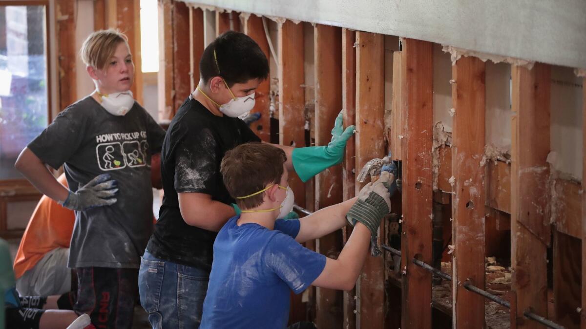 Young helpers strip a wall down to its studs in a flood-damaged home after Harvey moved through Houston.