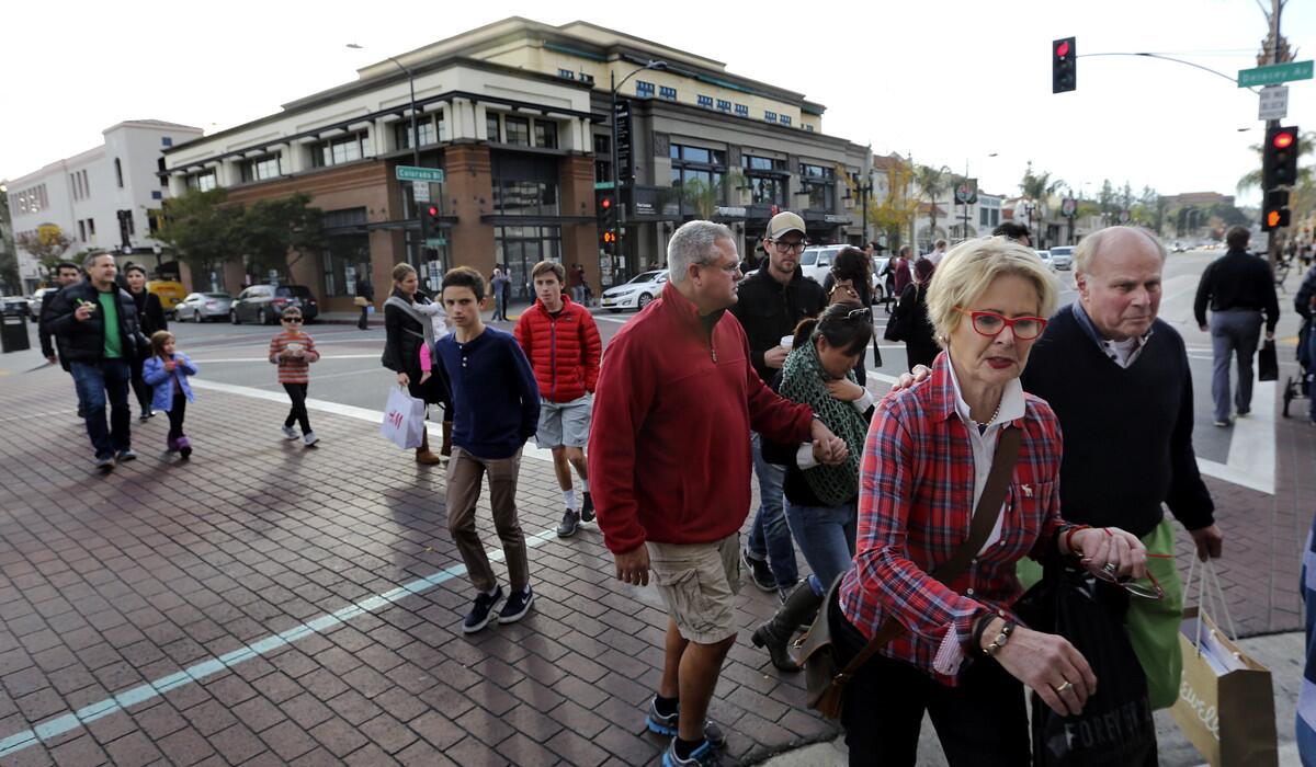 Pedestrians make their way across the street on Colorado Blvd. in Pasadena on Dec. 24.