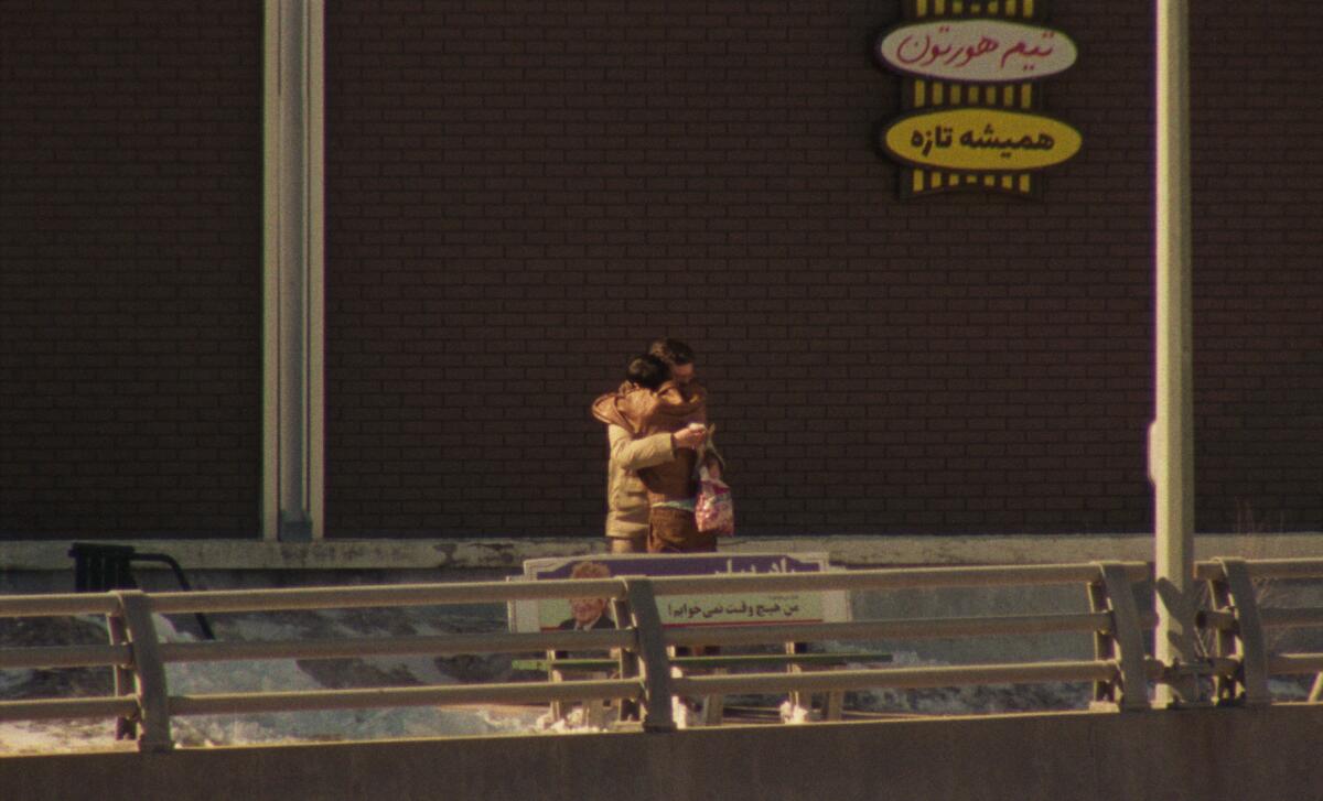 Two people hug on the street.