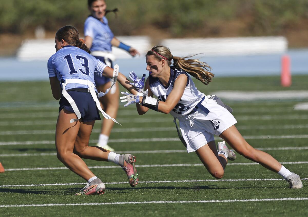 Corona del Mar's Bella Thomas (13) evades the rush of Newport Harbor's Audrey Burns (22) during Monday's game.