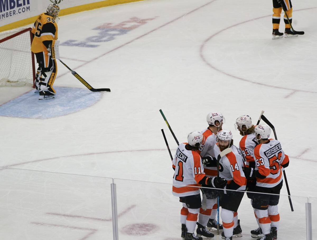 Philadelphia Flyers' Sean Couturier (14) celebrates with teammates after scoring against Pittsburgh Penguins goaltender Tristan Jarry (35) during the first period of an NHL hockey game Thursday, March 4, 2021, in Pittsburgh. (AP Photo/Keith Srakocic)