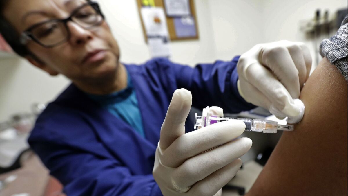 A medical assistant at a Seattle health clinic gives a patient a flu shot in January.