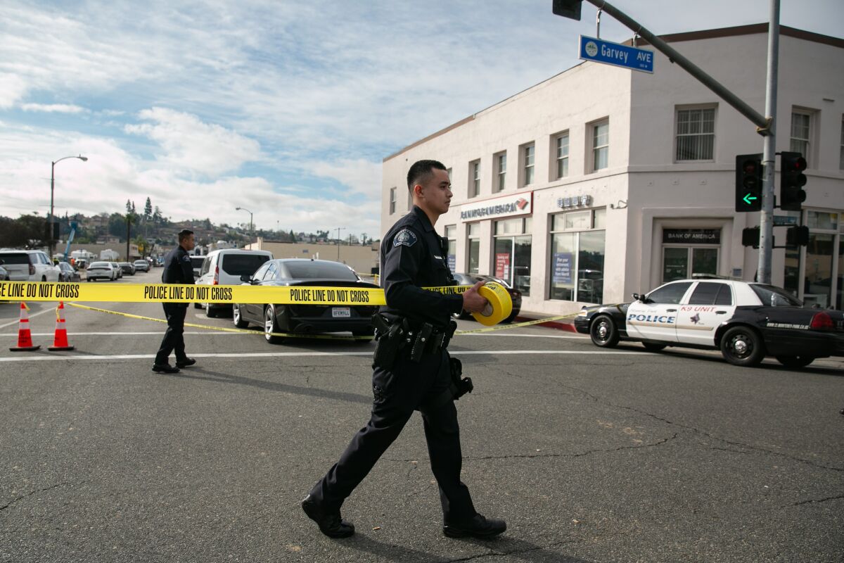 A police officer walks across a street marked off by yellow crime tape after a mass shooting in Monterey Park.