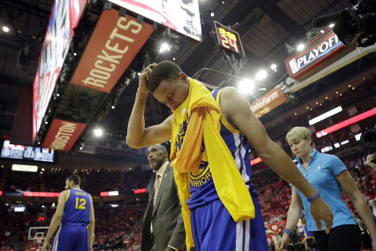 The Warriors' Stephen Curry leaves the court Sunday after spraining his right knee.