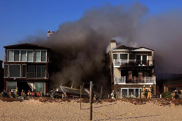 Firefighters from several departments attack a blaze that destroyed one multistory seaside home and heavily damaged two others Thursday afternoon in Sunset Beach, which is near Huntington Beach in Orange County. See full story