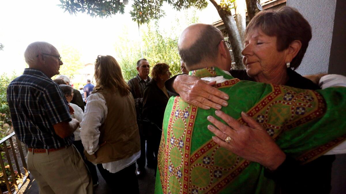 Jean Schettler hugs the Rev. Moses Brown after the Mass.