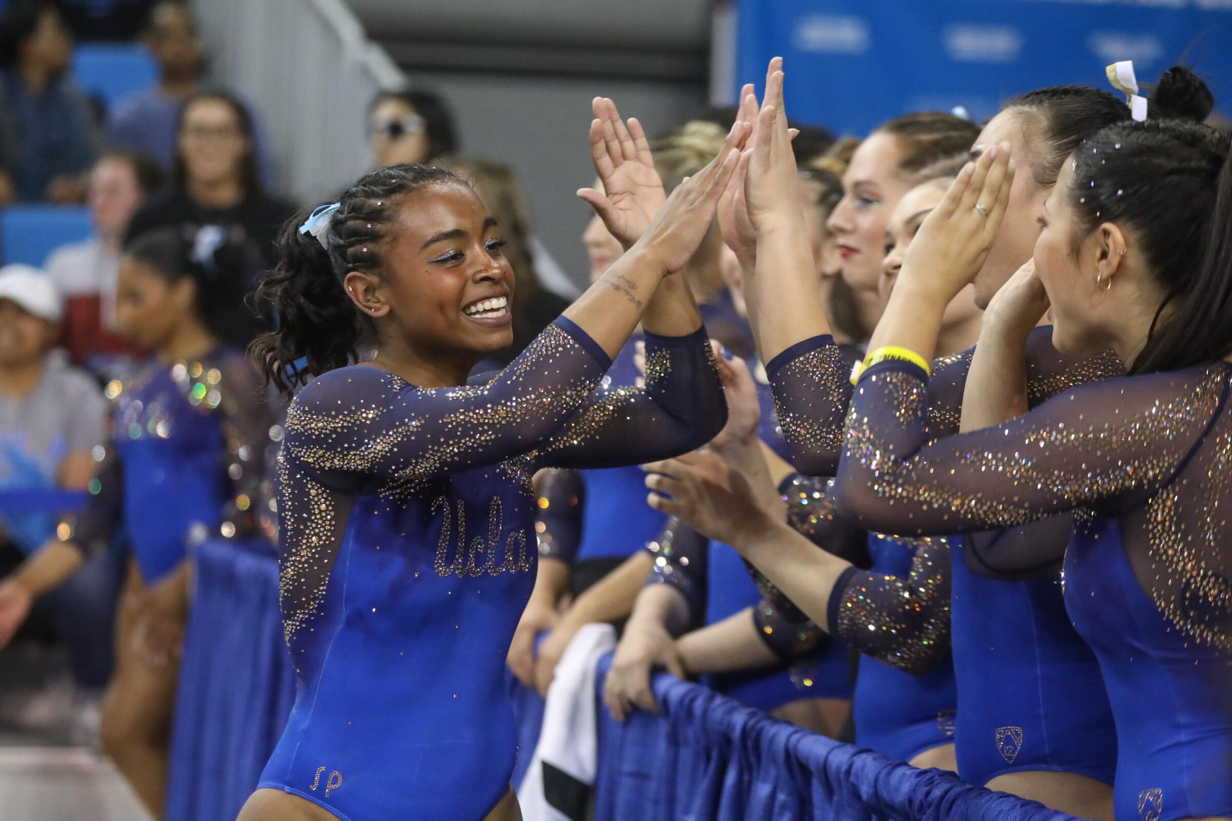 Selena Harris high fives her UCLA gymnastics teammates during the NCAA Los Angeles Regional