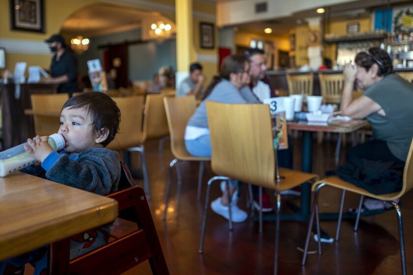 LOS ANGELES, CA - NOVEMBER 21: Ten month old Julian Medrano Rodriguez drinking milk at Amalia's Restaurant on Sunday, Nov. 21, 2021 in Los Angeles, CA. On Nov. 29, many establishments like Amalia's will be required to demand proof of vaccination for several months. (Francine Orr / Los Angeles Times)