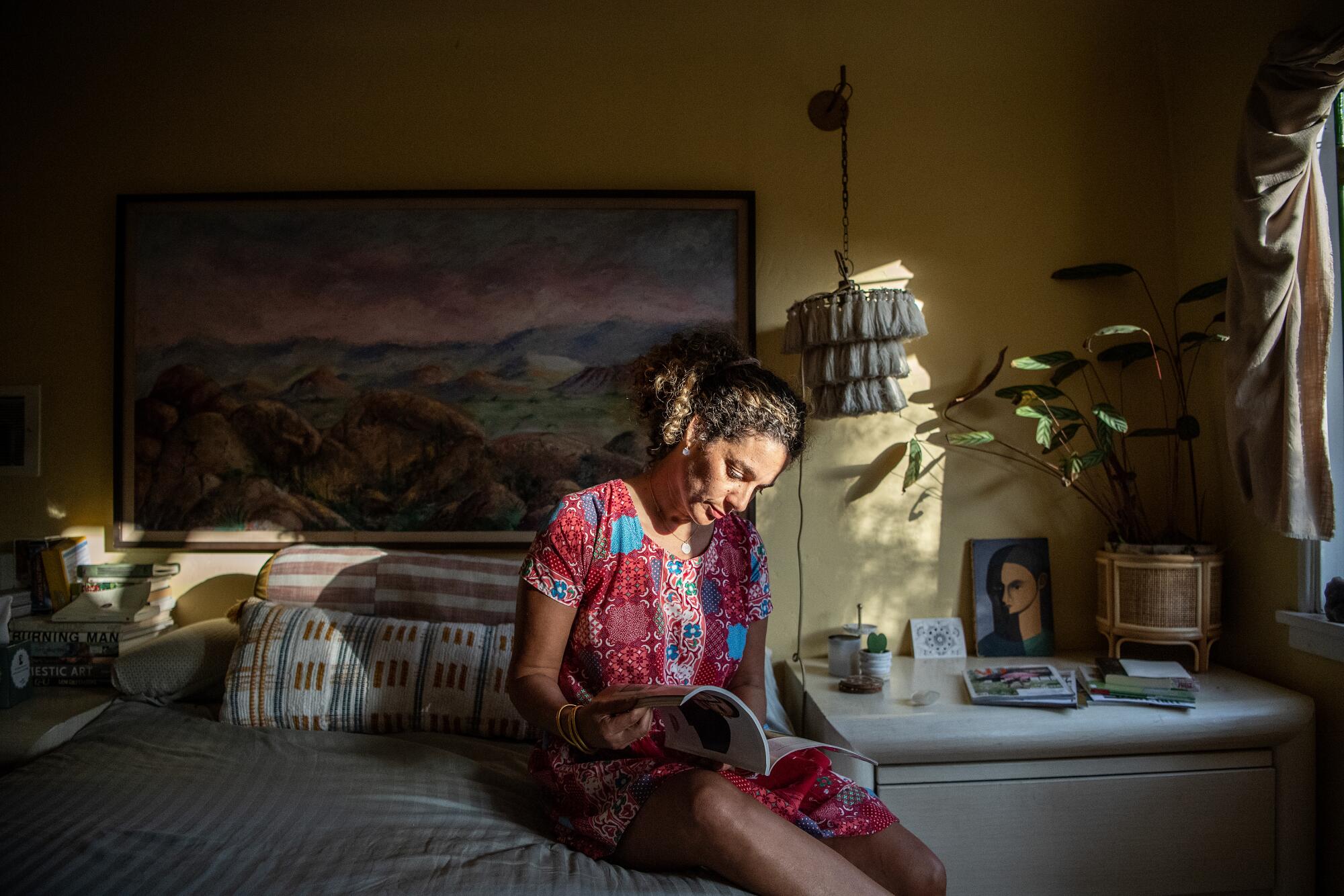 Faith Blakeney sitting on a bed looking down at a book.