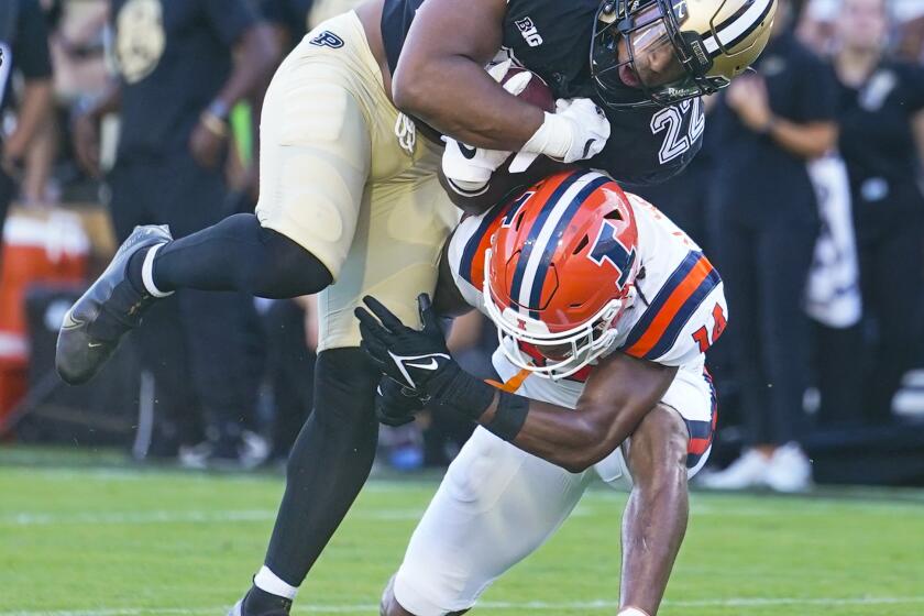 Purdue running back Dylan Downing (22) goes over Illinois defensive back Xavier Scott (14) on his way to a touchdown during the first half of an NCAA college football game in West Lafayette, Ind., Saturday, Sept. 30, 2023. (AP Photo/Michael Conroy)