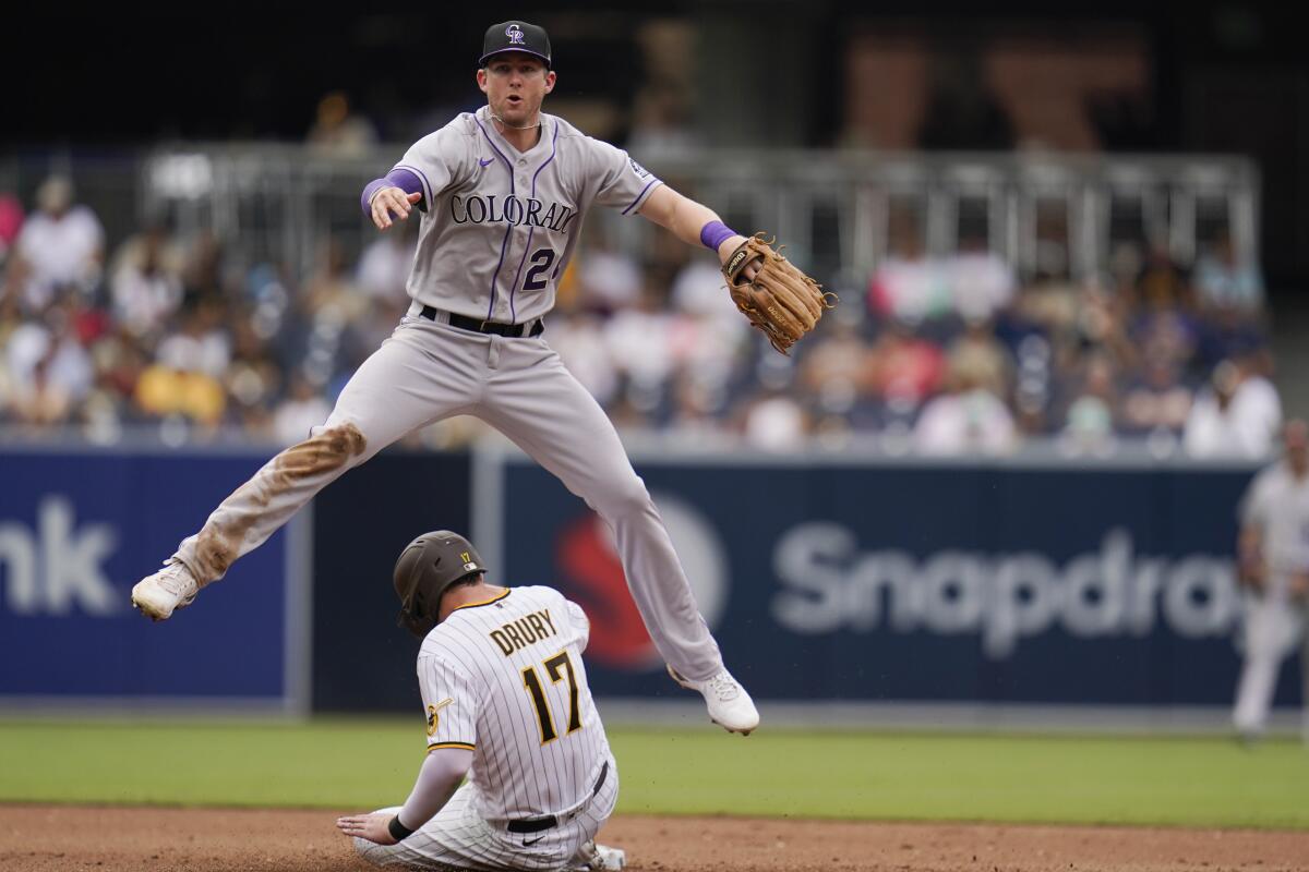 El segunda base de los Rockies de Colorado, Ryan McMahon, salta para evitar la barrida de Brandon Drury