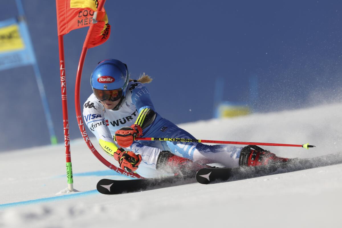 A woman leans into a turn on skis through the snow, hitting a red flag.