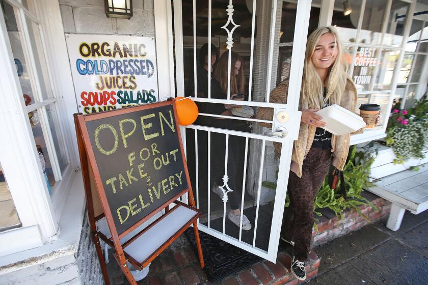 Rachel Miller, right, and sister Chloe get take-out sandwiches and coffee from the Orange Inn, a Laguna Beach favorite, as local businesses are being asked to avoid small gathering and uphold social distances during the widening Coronavirus pandemic.