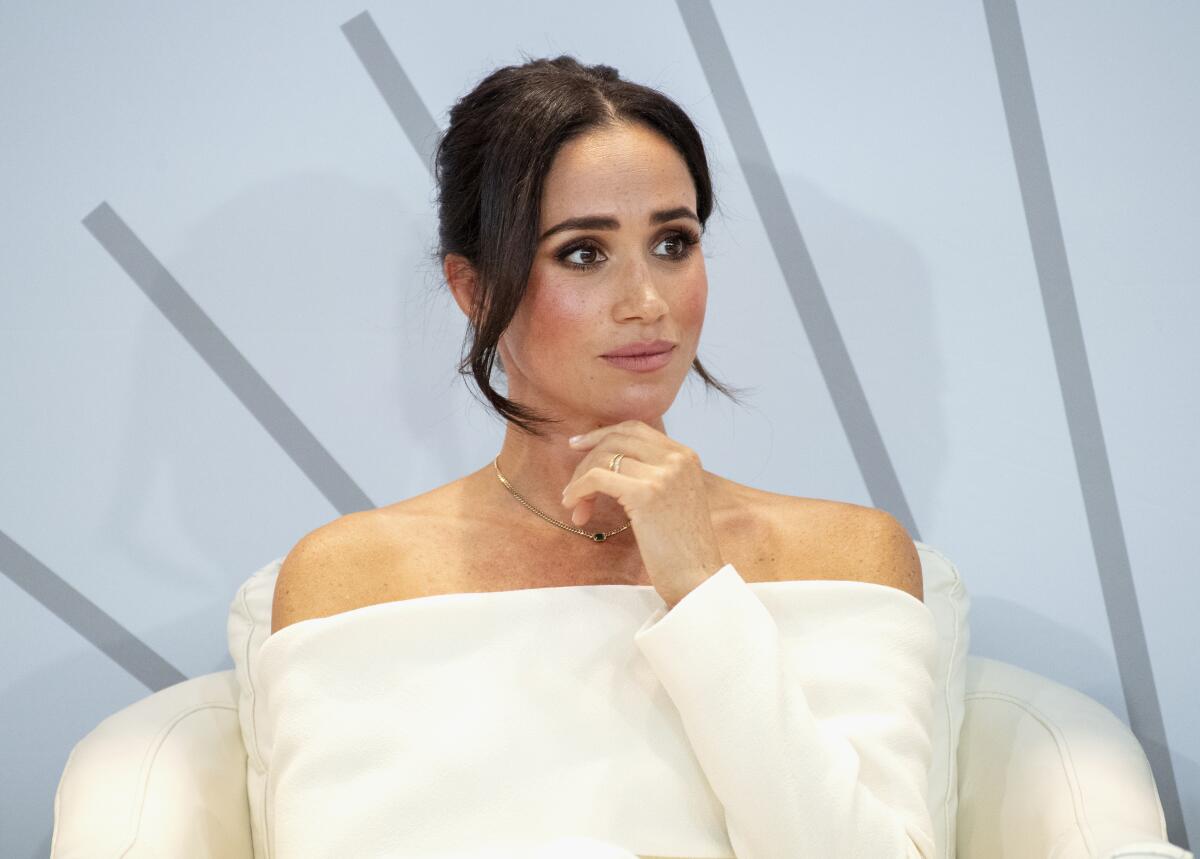 Meghan Markle wears a white gown and has her dark hair styled in an updo.