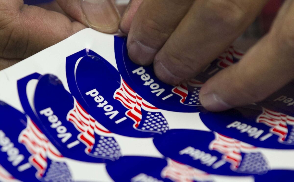 A poll worker peels stickers to hand out to voters in San Diego