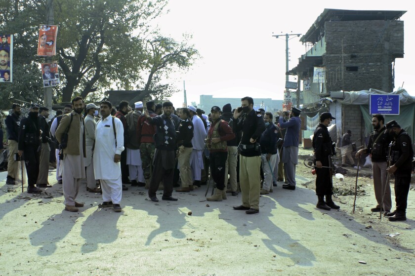 Police officers control an angry crowd protesting against a mentally unstable man accused of blasphemy, in Mandani, an area of Charsadda district, Pakistan, Monday, Nov. 29, 2021. Pakistani authorities said a mob burned a police station and four police posts in the northwest overnight and demonstrators wanted to lynch the man on charges that he desecrated the Quran, Islam’s holy book. (AP Photo/Zia Mohammad)