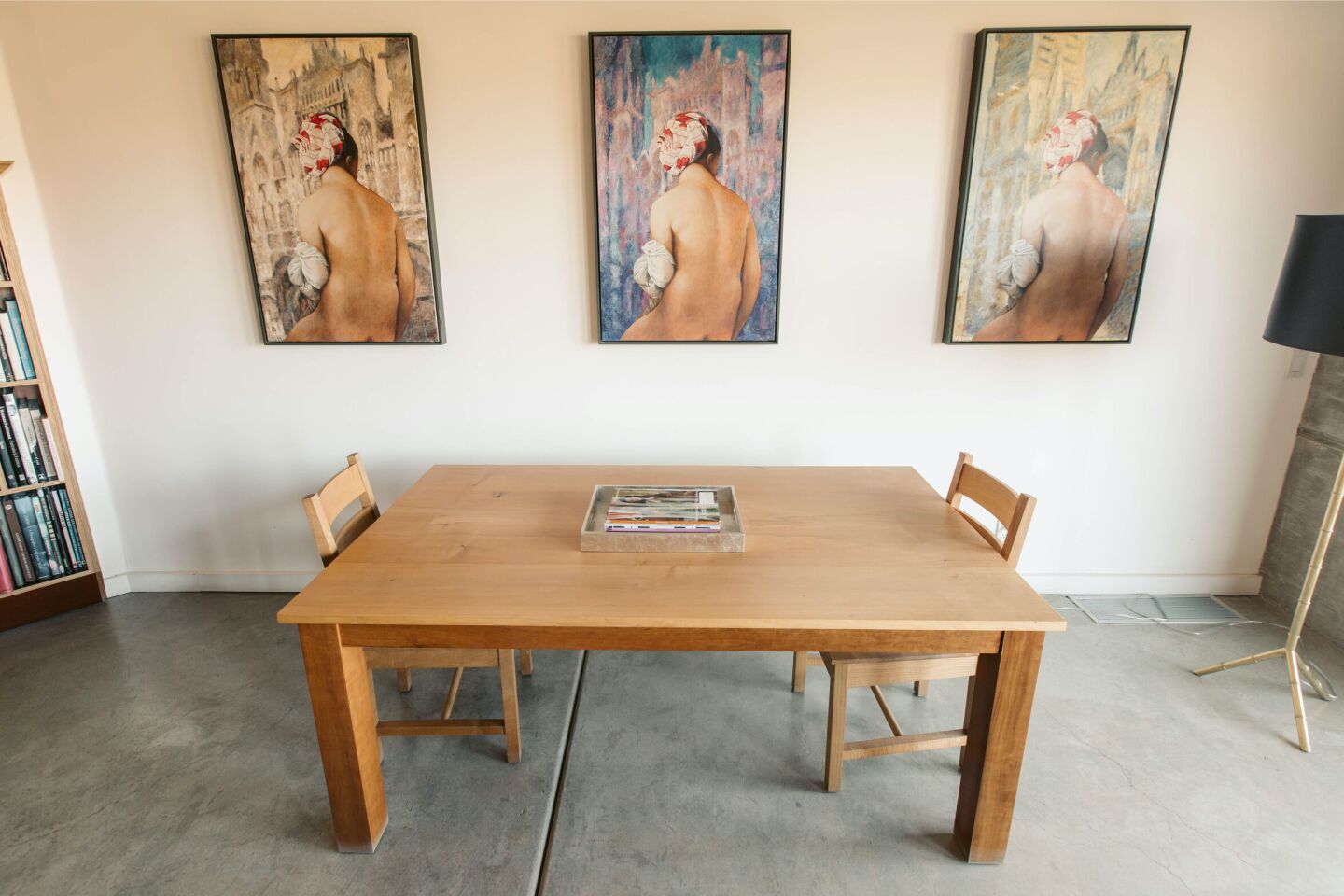 A table for two sits against a white wall with three works of art.