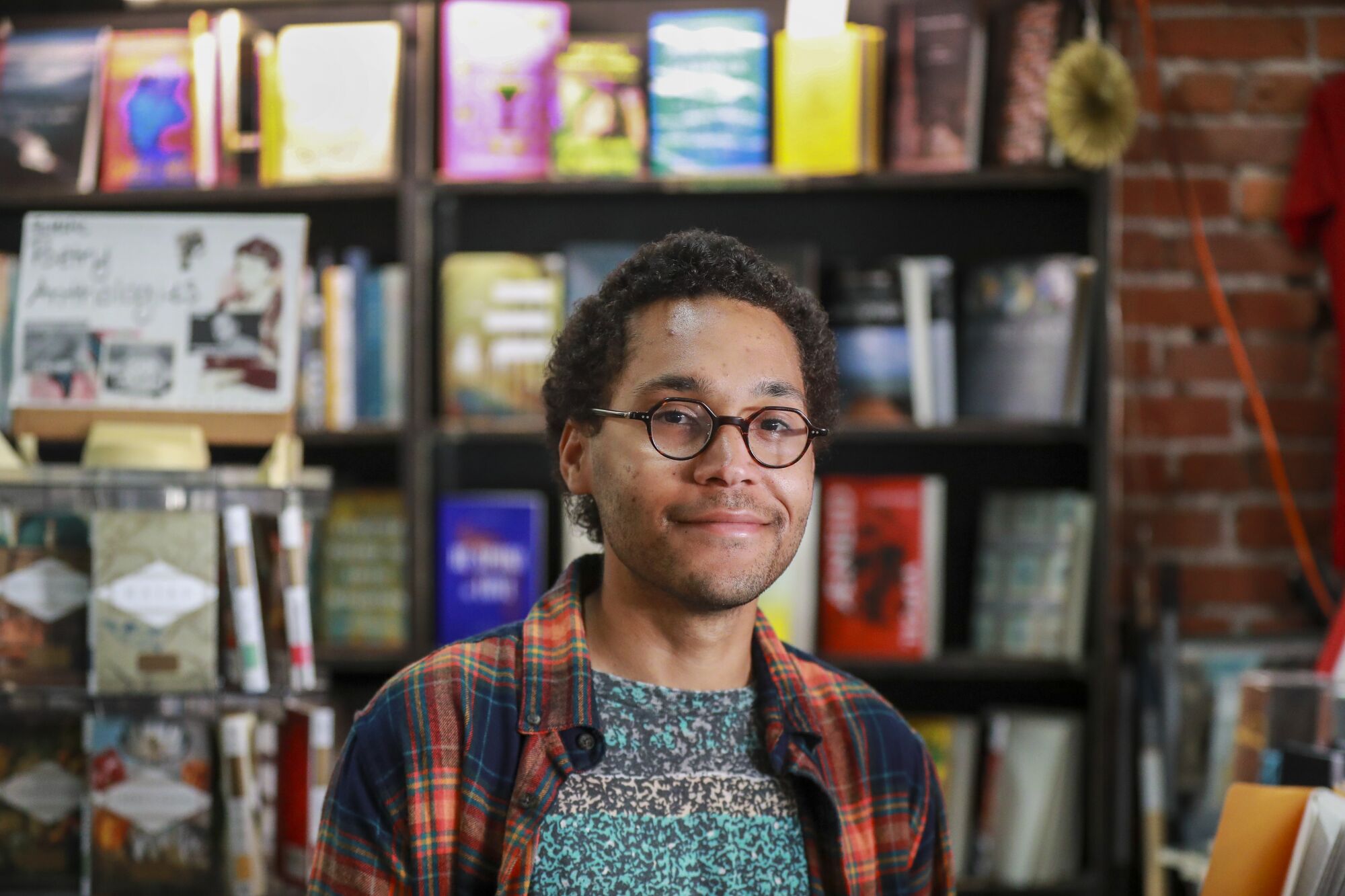 A man wearing a flannel shirt in a bookstore.