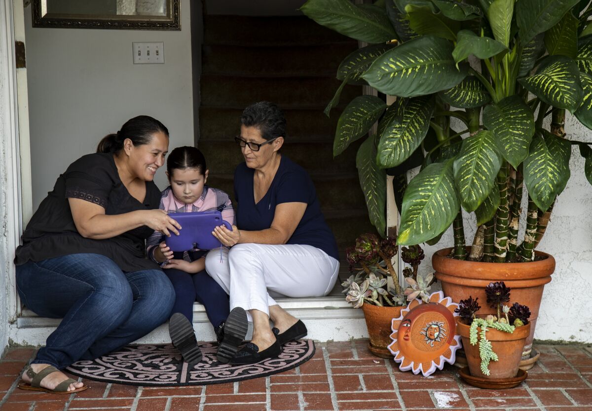 Mabel Gonzalez, left, her daughter Camila, 8, and mother, Teresa, FaceTime with Gonzalez's father, Francisco.