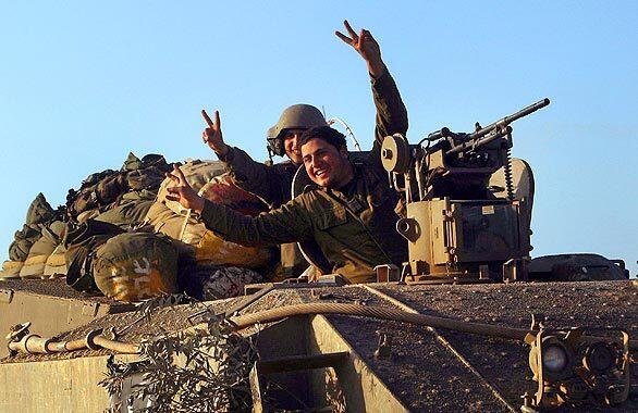 Israeli soldiers gesture from an armored personnel carrier at the start of a temporary ceasefire along the Israeli-Gaza border in Israel. Complete Coverage: • Conflict in Gaza