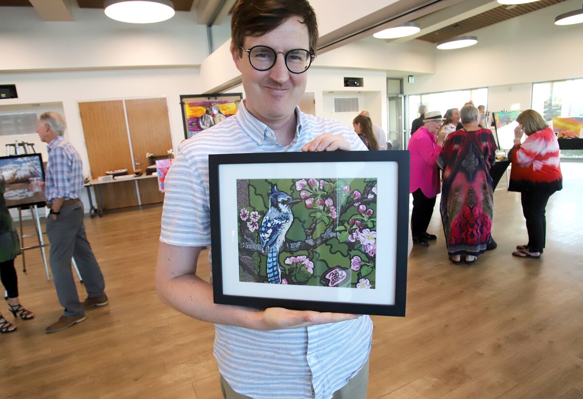 Zach Beckemeyer holds one of his artworks, "Blue-jay in a Cherry Tree." 