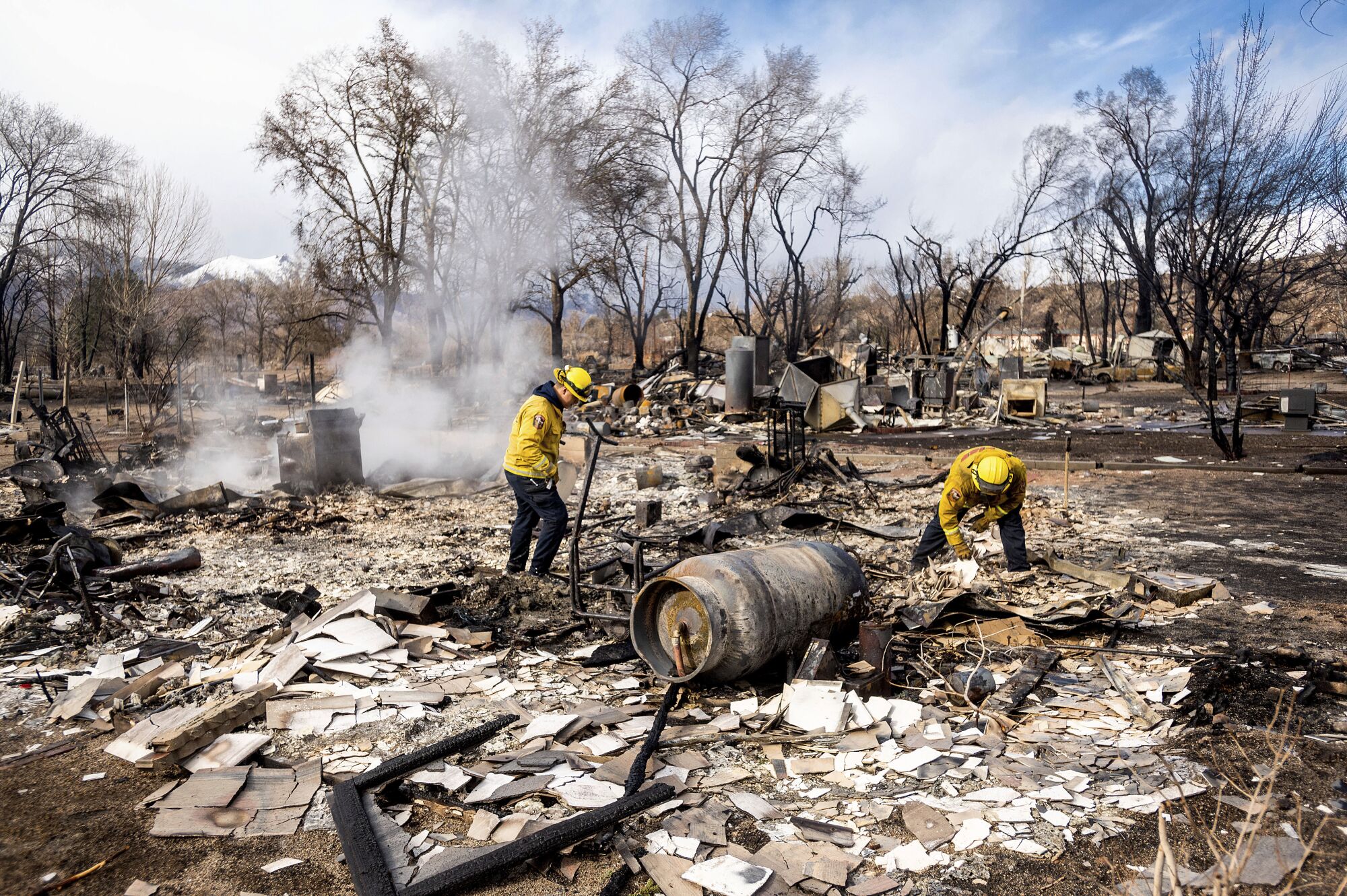 Firefighters stand in the burned wreckage of a home