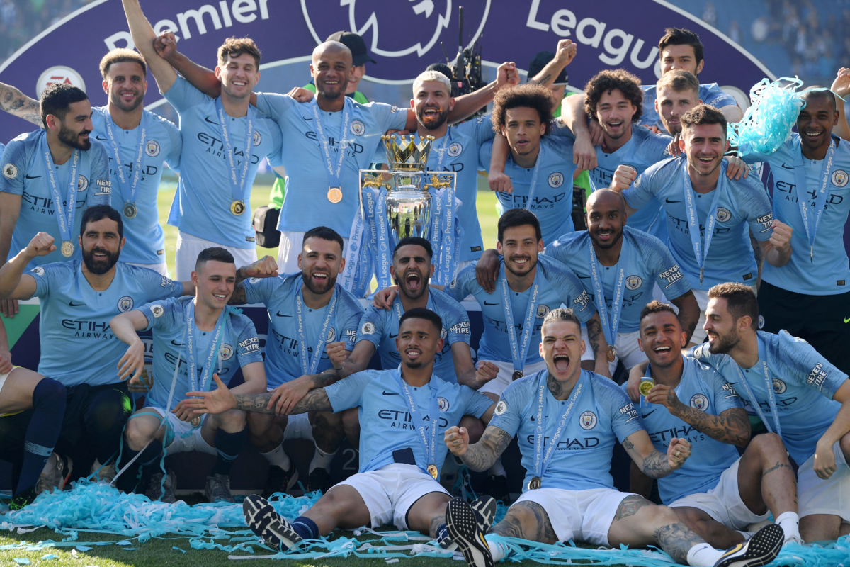Manchester City players celebrate with the Premier League Trophy.