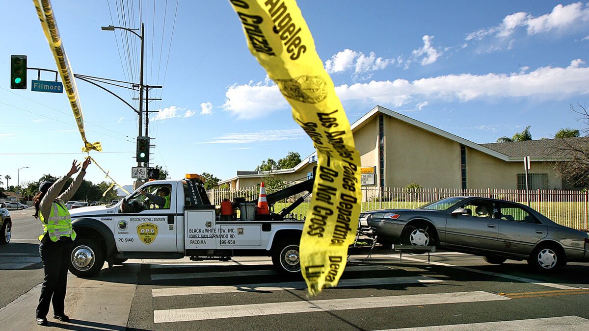 A car is towed away after a woman was shot and killed last August in Pacoima.